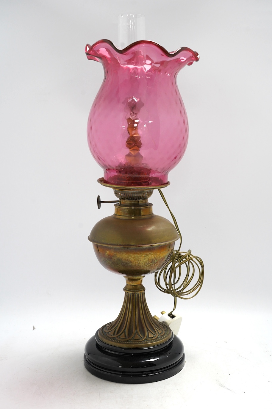 A Victorian brass oil lamp with cranberry glass shade. Condition - fair
